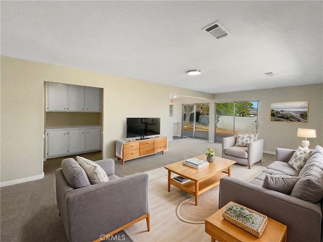 living room with a textured ceiling, a notable chandelier, and light wood-type flooring