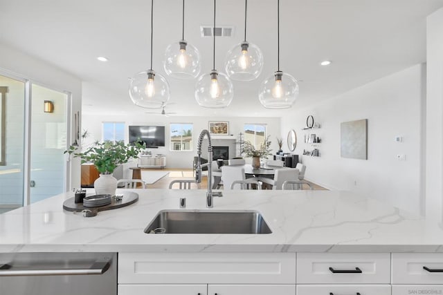 kitchen featuring white cabinetry, sink, pendant lighting, and light stone countertops