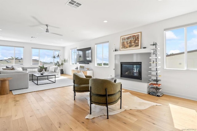 living room featuring ceiling fan, light hardwood / wood-style floors, and a healthy amount of sunlight