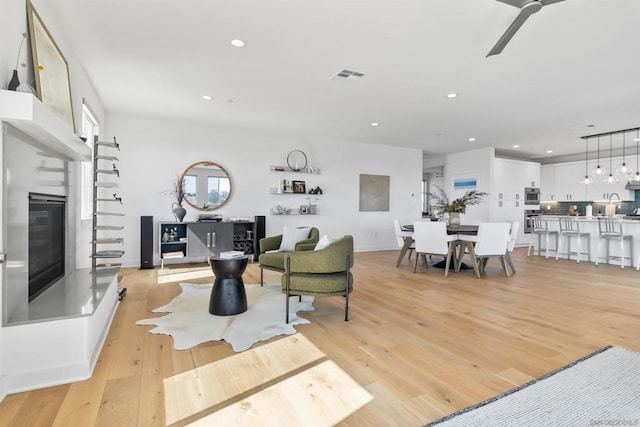 living room with ceiling fan and light hardwood / wood-style flooring