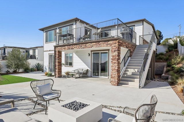 back of property featuring a balcony, an outdoor fire pit, and a patio