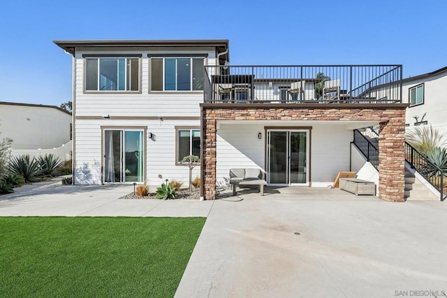 rear view of house featuring a balcony, a yard, and a patio area