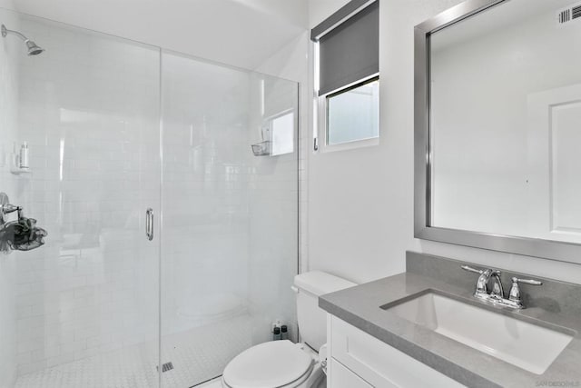 bathroom with vanity, a shower with shower door, and toilet