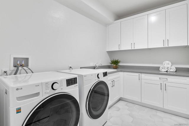 laundry area featuring sink, light tile patterned floors, cabinets, and washing machine and clothes dryer