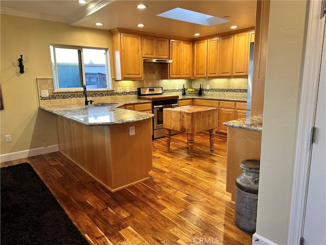 kitchen with a skylight, stainless steel range, sink, kitchen peninsula, and light hardwood / wood-style floors