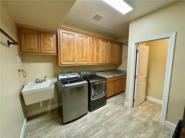 clothes washing area featuring washer and clothes dryer, cabinets, and sink