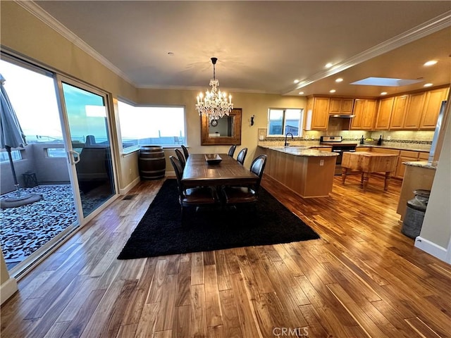 dining room featuring a skylight, sink, hardwood / wood-style floors, and ornamental molding