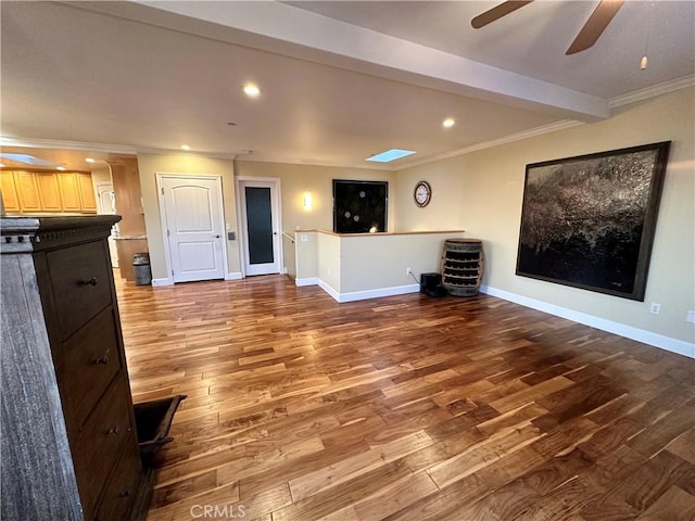 unfurnished living room featuring a skylight, crown molding, hardwood / wood-style floors, and ceiling fan