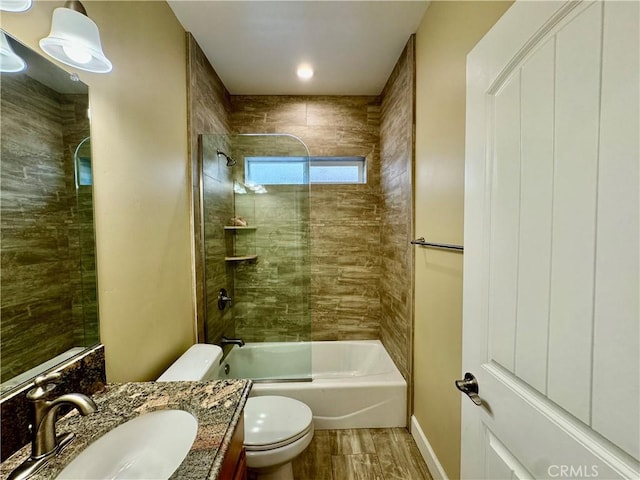 full bathroom featuring hardwood / wood-style floors, vanity, toilet, and tiled shower / bath