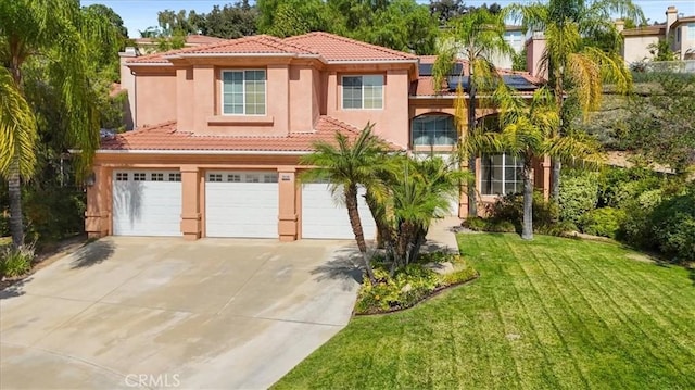 mediterranean / spanish home featuring a front lawn and a garage