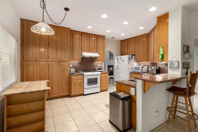 kitchen featuring kitchen peninsula, a kitchen breakfast bar, white appliances, sink, and decorative light fixtures