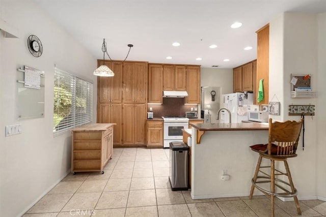 kitchen featuring white appliances, hanging light fixtures, light tile patterned floors, a kitchen bar, and kitchen peninsula