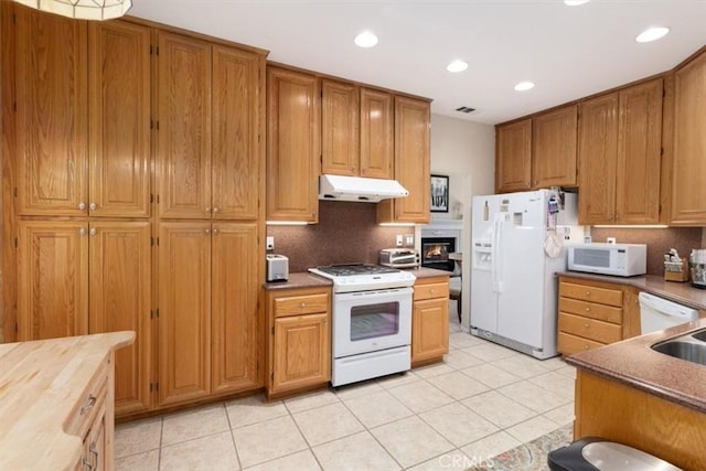 kitchen with decorative backsplash, white appliances, and light tile patterned flooring