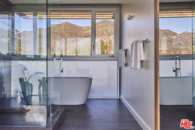 bathroom with hardwood / wood-style flooring, a mountain view, and a tub to relax in