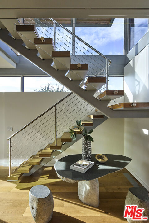 stairs with a wealth of natural light and hardwood / wood-style floors