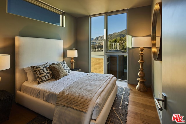 bedroom featuring stainless steel refrigerator, a mountain view, and hardwood / wood-style flooring