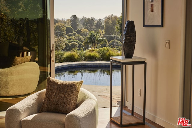 sitting room with a water view and hardwood / wood-style flooring