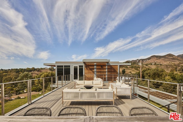 deck featuring outdoor lounge area, a mountain view, and a sunroom