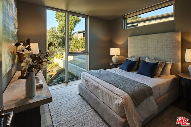 bedroom with hardwood / wood-style floors, access to exterior, and a wall of windows