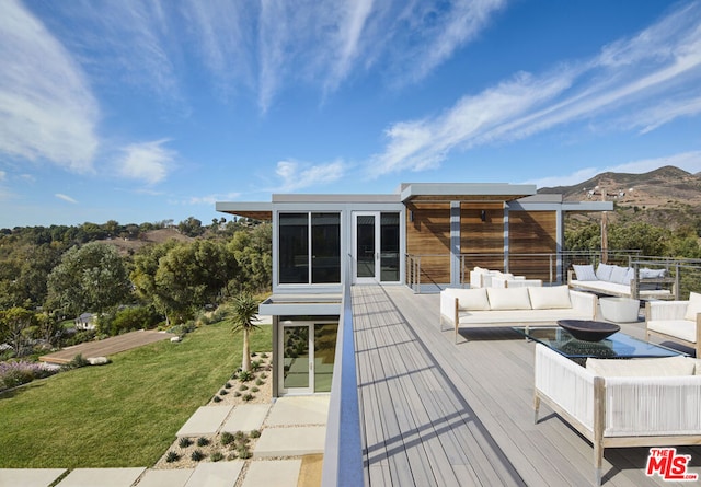 wooden terrace with a sunroom, an outdoor living space, a mountain view, and a yard