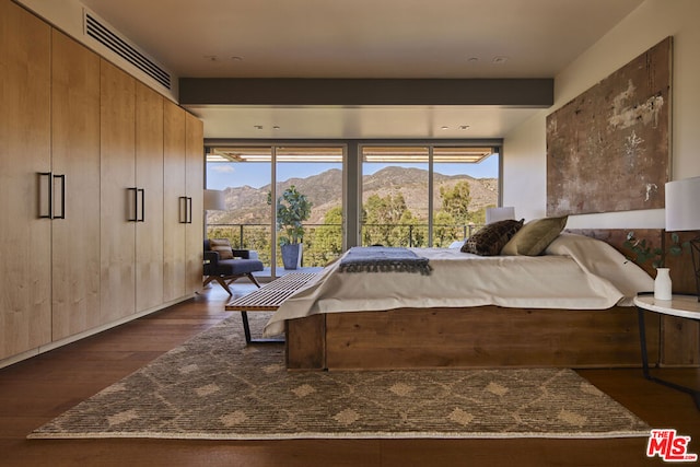 bedroom with a mountain view, access to exterior, and dark wood-type flooring