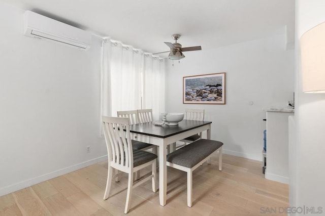 dining area featuring light wood-type flooring, ceiling fan, and a wall mounted air conditioner