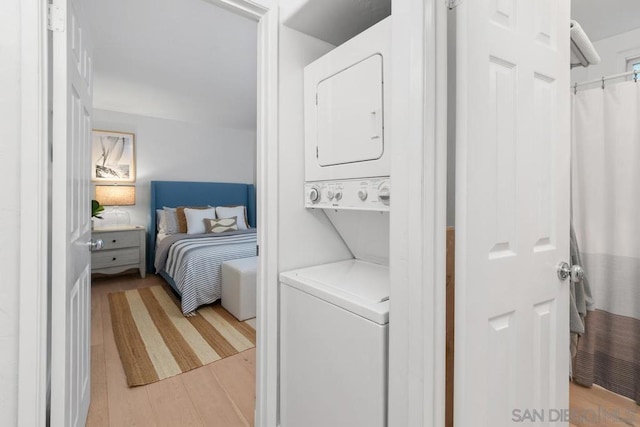 washroom featuring stacked washer / dryer and light hardwood / wood-style flooring