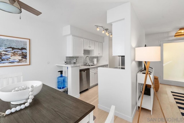 kitchen featuring white cabinetry, stainless steel dishwasher, backsplash, and sink