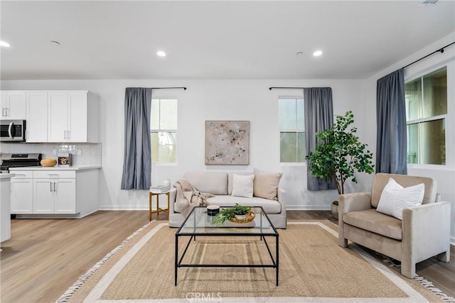 living room featuring a wealth of natural light, baseboards, recessed lighting, and light wood finished floors