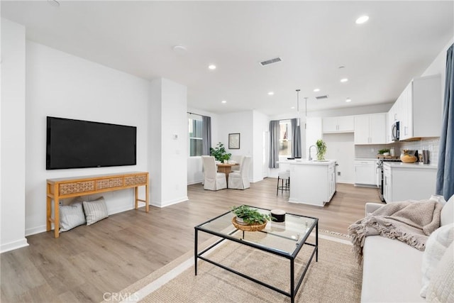 living area featuring light wood finished floors, visible vents, recessed lighting, and baseboards