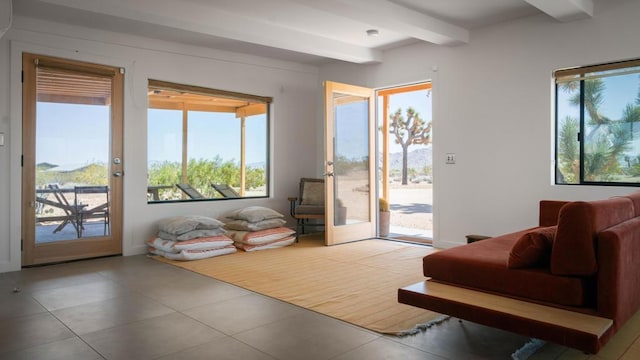 doorway with tile patterned flooring, beam ceiling, and a wealth of natural light