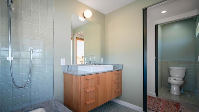 bathroom with tile patterned flooring, vanity, toilet, and tile walls