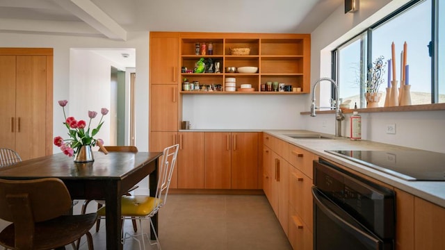 kitchen with black appliances, light tile patterned floors, sink, and beamed ceiling