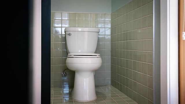 bathroom featuring toilet and tile walls