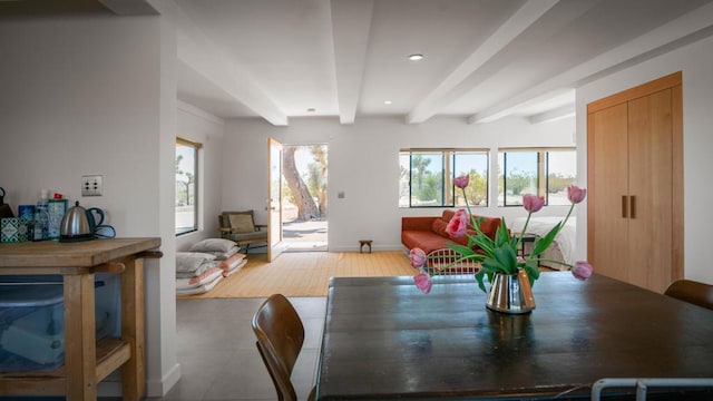 dining room featuring beam ceiling, a healthy amount of sunlight, and wood-type flooring