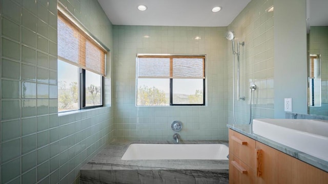 bathroom featuring vanity, a tub to relax in, and tile walls