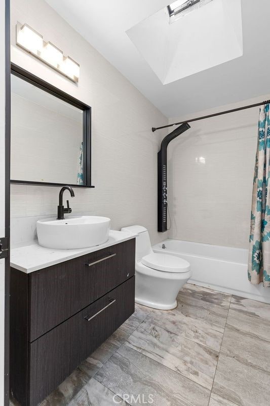 full bathroom with shower / bath combination with curtain, vanity, and toilet