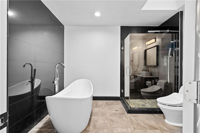 full bathroom featuring shower with separate bathtub, toilet, tile walls, and sink