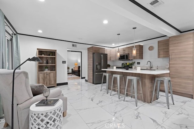 kitchen with appliances with stainless steel finishes, a kitchen breakfast bar, sink, beamed ceiling, and hanging light fixtures