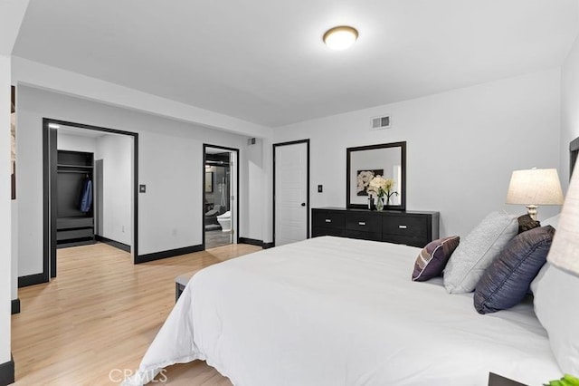 bedroom featuring light wood-type flooring and ensuite bath