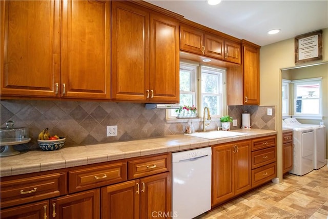 kitchen with tile counters, dishwasher, sink, decorative backsplash, and washer and dryer