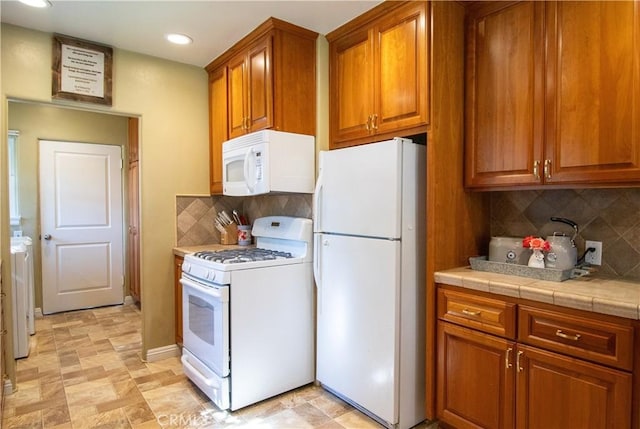 kitchen featuring backsplash, tile counters, and white appliances