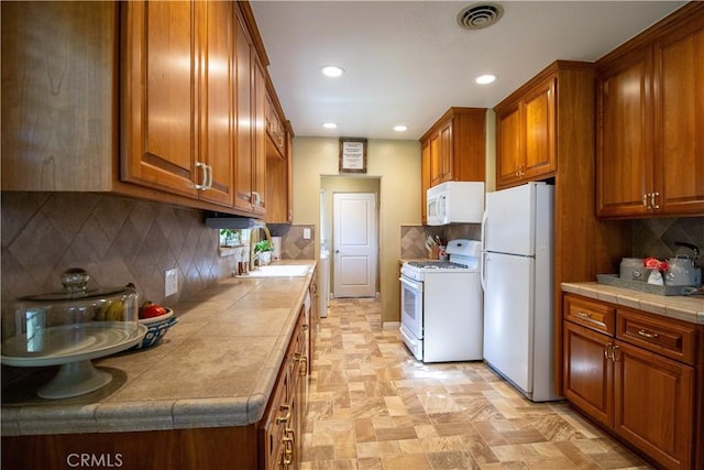 kitchen with tile countertops, decorative backsplash, sink, and white appliances