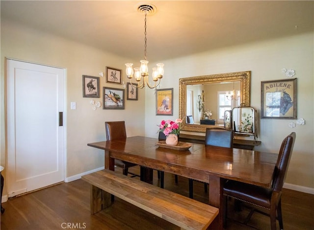 dining room with dark wood-type flooring and an inviting chandelier