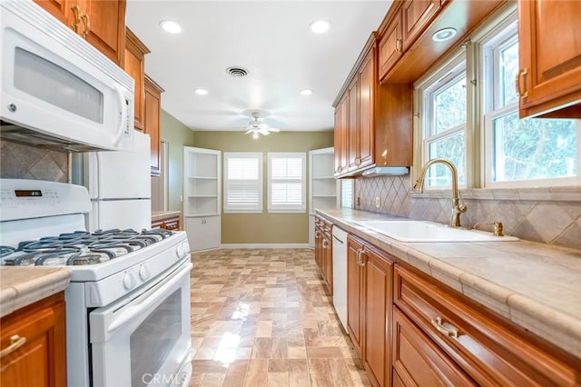 kitchen with brown cabinets, white appliances, and a sink