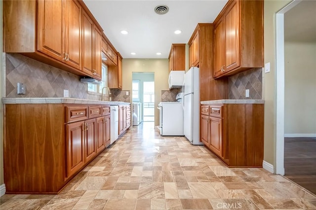 kitchen with visible vents, white appliances, baseboards, and brown cabinetry