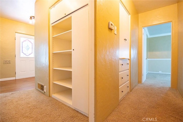 hall featuring visible vents, carpet, and ornamental molding