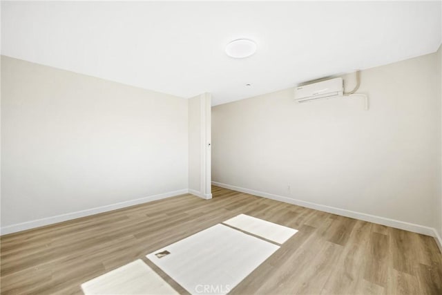 unfurnished room featuring an AC wall unit and light hardwood / wood-style flooring