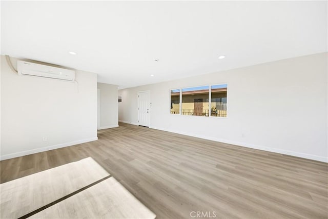 unfurnished living room featuring hardwood / wood-style floors and an AC wall unit