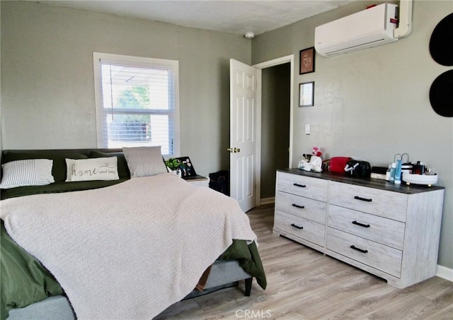 bedroom featuring light hardwood / wood-style floors and a wall mounted AC